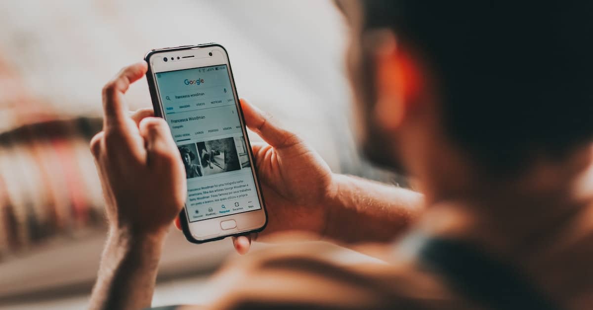 A man is holding a smartphone with a social media app for remarketing.